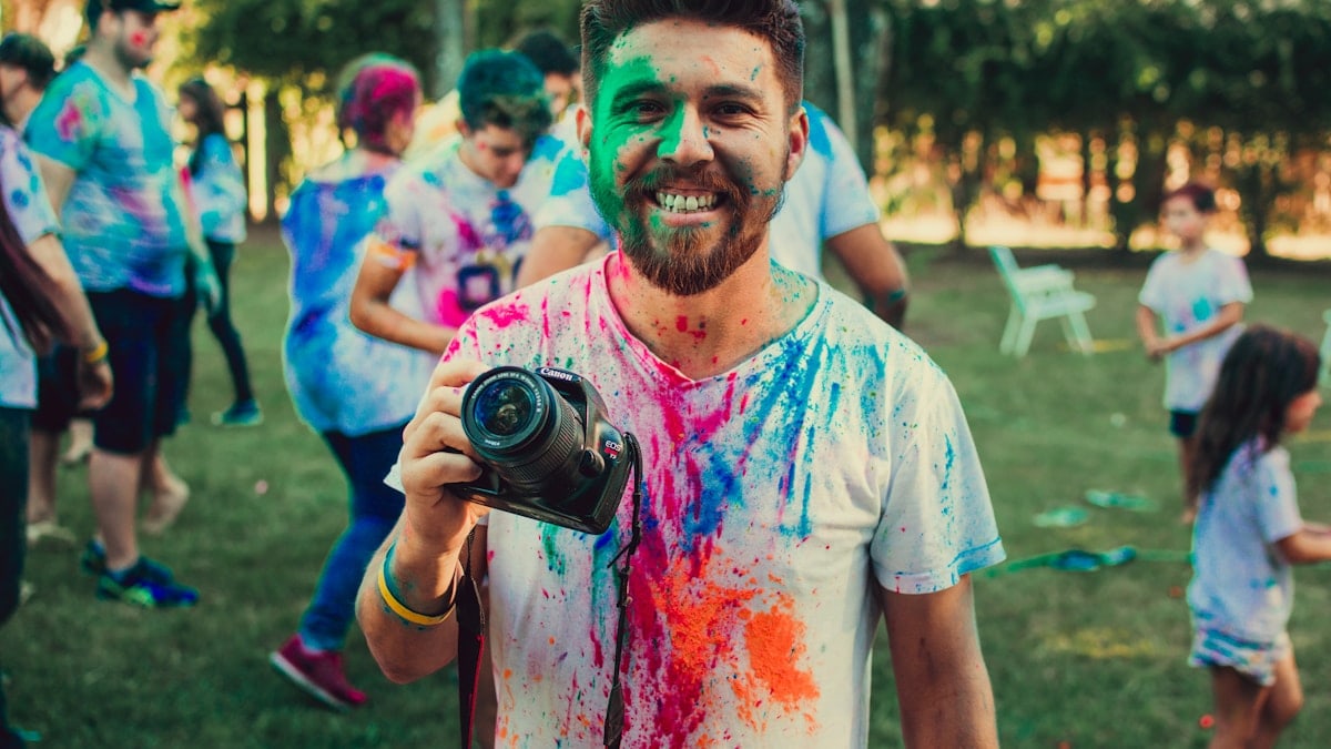 man holding DSLR camera with paint on face